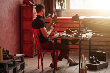 back view photo. hardworking shoemaker repairing the sole of a shoe