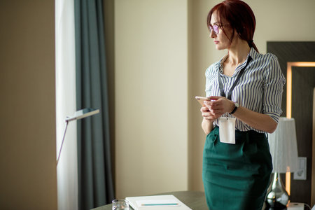 Female assistant, arriving for a business conference in famous hotel reports by telephone to the...