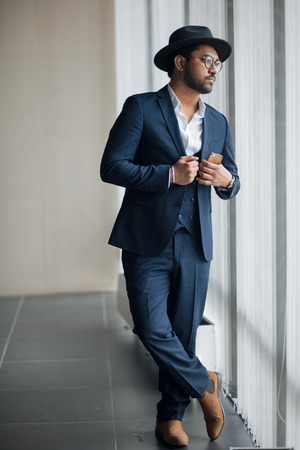serious pensive guy in blue suit is standing with crossed legs and waiting somebody. full length photo.の写真素材