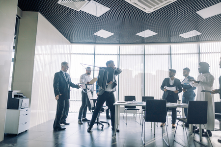 Aggressive unsatisfied angry mad crazy colleagues are having scandal at conference room, caucasian man is going to throw a chair into a rival, panoramic view.の写真素材