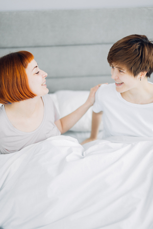beautiful cheerful women laughing while sitting on bed. close up photo. happiness, free timeの写真素材