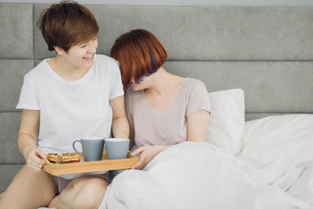 funny gorgeous sisters talking about something interesting while resting on the bed. close up photo. copy spaceの写真素材