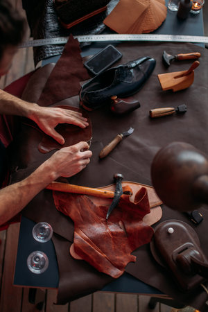 guy working with leather using crafting tool at workshop. close up cropped photo. busy working day