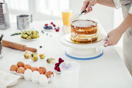 talented chef assembling the cake layers. detail steps on how to make cake, close up cropped photoの写真素材