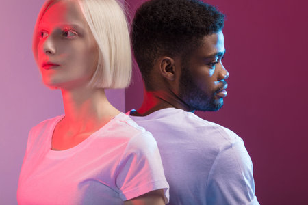 woman with white skin and man with black skin standing back to back, close up photo. isolated...