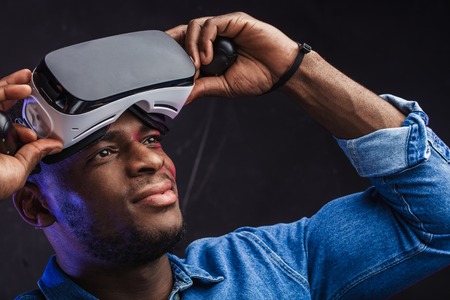 African male architector taking off his virtual reality headset looking around, can not believe that it is only digital images, and his and his skillfully built house does not yet exist in reality.の写真素材