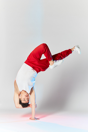 Free style dancer in red sports trousers doing some acrobatic stunts dancing break dance isolated over white studio backgroundの写真素材