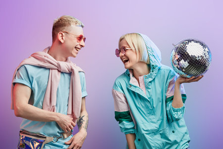 A couple of young stylish blonde female and albino male dancers wearing pink sunglasses and mint...