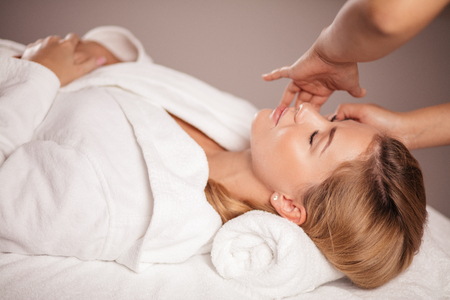 gorgeous woman enjoys spa treatment in the clinic. close up side view photo. girl takes care of her faceの写真素材