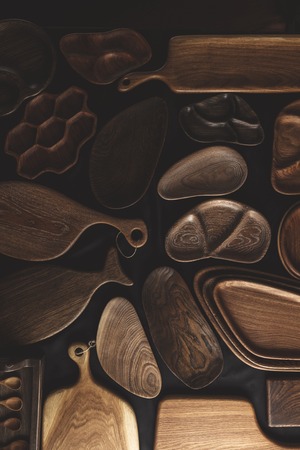Rich variety of wooden empty cutting boardsandplates on dark background, top view. Mockup of dishes for restaurant servingの写真素材