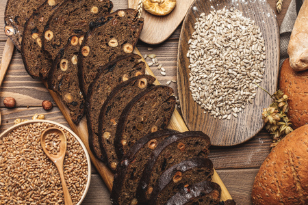 Homemade DIY, organic, healthy bread made of whole rye and wheat flour, hazelnut and seeds: sesame, chia, coriander , laid out on a wooden table.の写真素材