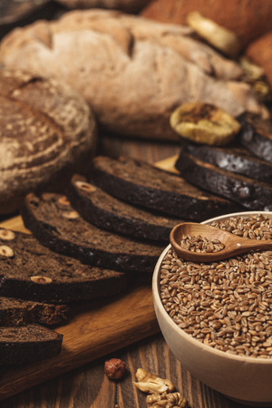 Homemade DIY, organic, healthy bread made of whole rye and wheat flour, hazelnut and seeds: sesame, chia, coriander , laid out on a wooden table.の写真素材