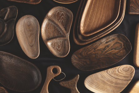 Rich variety of wooden empty cutting boardsandplates on dark background, top view. Mockup of dishes for restaurant servingの写真素材