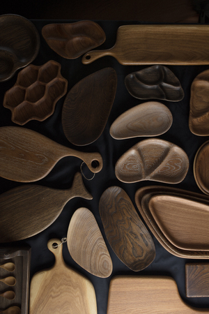 Set of cutting boards and DIY kitchen wooden utensils, plates and dishes made from oak, walnut and pine wood isolated on dark background.の写真素材