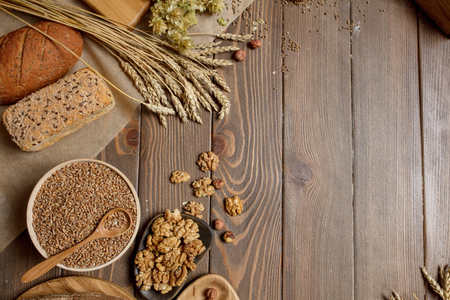 Whole grain, whole loaf and sliced pieces of multigrain bread contains whole grains (poppy, millet, flaxseed, pumpkin seeds, and sunflower seeds) isolated on dark wooden table with a copyspace.の写真素材