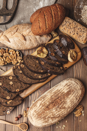 Homemade DIY, organic, healthy bread made of whole rye and wheat flour, hazelnut and seeds: sesame, chia, coriander , laid out on a wooden table.の写真素材