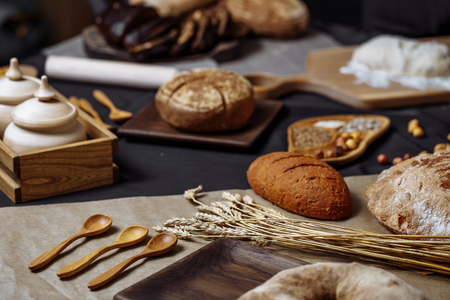 Homemade DIY, organic, healthy bread made of whole rye and wheat flour, hazelnut and seeds: sesame, chia, coriander , laid out on a wooden table.の写真素材