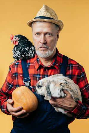 Healthy food. Portrait of surprised farmer wearing special clothes isolated on yellow background. free time. hobby. interest.の写真素材