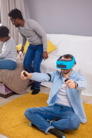 Group of multicultural friends having fun at home playing 3D game using hi-tech virtual reality...