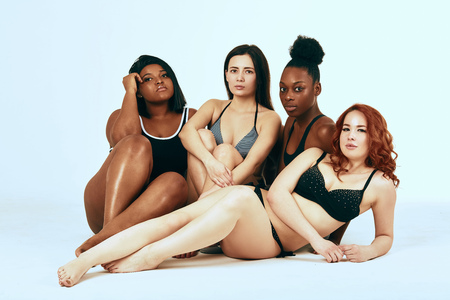 Multi-ethnic beauty. Different ethnicity women - Caucasian, African, Latin, Hispanic beautiful adult girlfriends posing in underwear isolated over white studio background.の写真素材