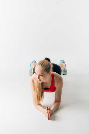 blonde athlete is practicing press ups with elbows, full length shot, isolted white background.の写真素材