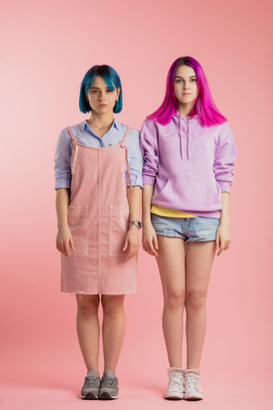 two  girls standing still and looking at camera. full length photo. serious girls showing the changes of their appearance. what color of hair is the best choose any variants of coloring hairの写真素材
