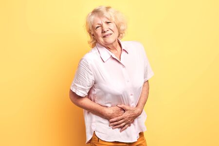 blonde woman having pain in the liver. Syros liver. Close up. Isolated yellow background.illness conceptの写真素材
