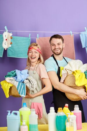 young couple rejoicing at washing process.happy family get pleasure from doing laundry. close up portrait. isolated blue backgroundの写真素材