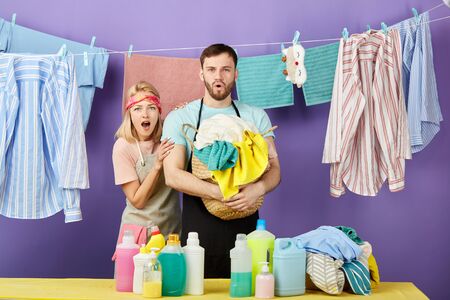 Shocked emotional couple having much work to do being in panic. isolated blue background, studio shot. emotiona and feeling.clean clothes hanging on the clotheslineの写真素材