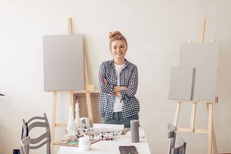 happy positive blond female artist standing with crossed arms and posing to the camera. close up photo.free time. spare time. lifestyleの写真素材