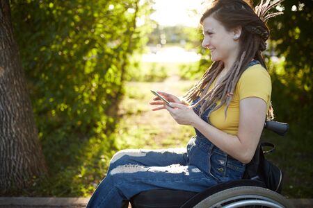 smiling disabled woman reading message on her smartphone.の写真素材