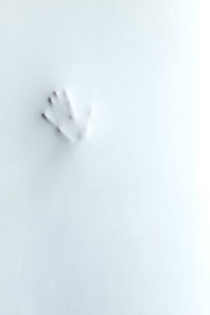 Silhouette of mans palm.gesture, body language. simbol, hi, hello, greeting, handprint of mad woman.horror mans face. hand behind the frosted glassの写真素材