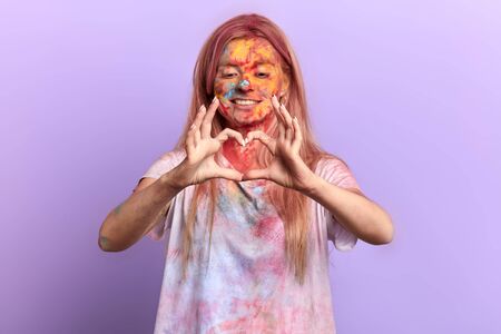 beautiful happy romantic girl making a heart from fingers. isolated blue background, studio shot, favourite holiday, girl felling in love. body language, sign, symbol, gestureの写真素材