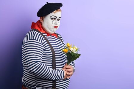 unhappy clown with flowers in hands being bullied, offended by somebody. close up portrait, copy space. place for text, advert ,の写真素材