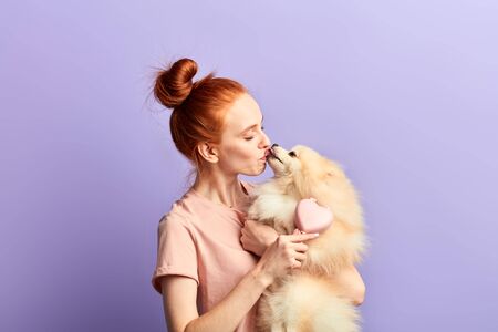 fluffy dog licking her owner as it shows devotion. close up photo. love, warm feeling and emotion, tenderness, isolated blue background, studio shotの写真素材