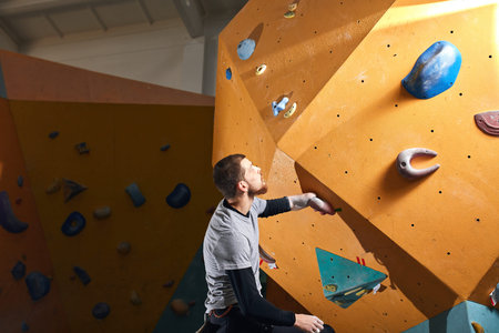 Young motivated rock-climber trains hard in climbing gym club, gets ready to bouldering competition among people with physical disabilities. Motivation and sport concept.