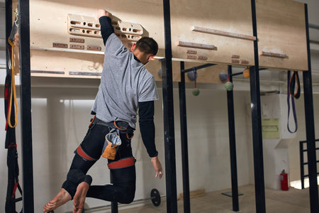 Rare view of unrecognizable young boulderer with physical disability doing exercises at special...