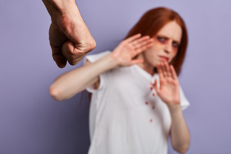 focus on clenched mans fist. woman protecting herself from cruel maniac. blurred background, studio...