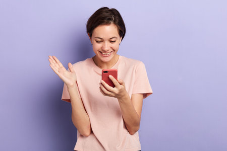 happy girl raising her hand, holding mobile phone watching funny video, photos, surfing the net,...