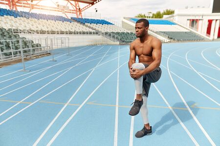 motivated strong runner stretching leg in the stadium, full length photo. copy space. health and body careの写真素材