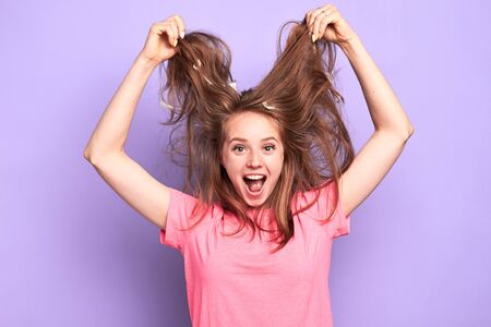 Waist up view of excited suprised pretty girl jumping happily, cant believe in her luck, glad to win first prize in competition, holding her messy hair, extremely emotional, shouting loudly.の写真素材