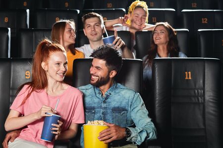 bearded handsome guy hugging his girlfriend enjoying the date in the cinema hall. close up photoの写真素材