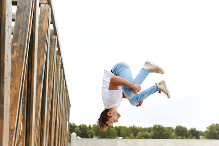 young man in comfortable stylish casual clothes doing crazy stunts, full length side view photo, man...