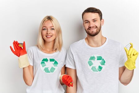 Recycling, reuse, energy.happy couple recycling symbol in their white T-shirts sorting batteries,cliose up portrait, studio shot, lifestyle, interest , environmental problemの写真素材