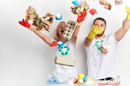 excited happy young couple having fun with litter, isolated white background, studio shot, man and woman throwing waste up, messy room. happiness conceptの写真素材