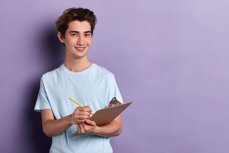 cute cheerful journalist writing a report. writer making up a story. close up portrait, isolated blue background, copy spaceの写真素材