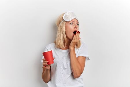 sleepy beautiful girl closing her mouth with a palm isolated white background, facial expression, relaxtion, girl doesnt want to go to workの写真素材