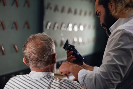 Cropped closeup photo of a handsome barber trimming beard to his client. close up back view photo.の写真素材