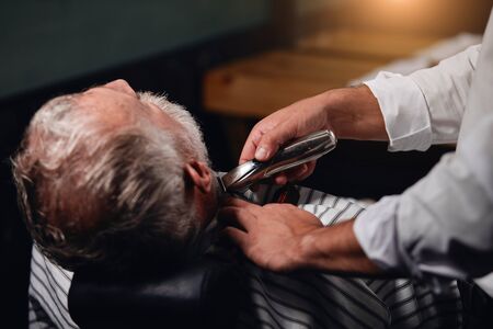 barber using electro shaver while working at beauty salon, close up back view photoの写真素材