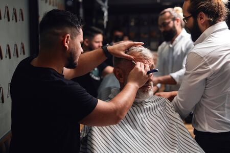 two professional masters working with old man, helping him to be handsome and stylish. close up photoの写真素材